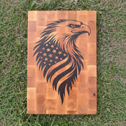 Wooden cutting board with an eagle and American flag design on a grassy background