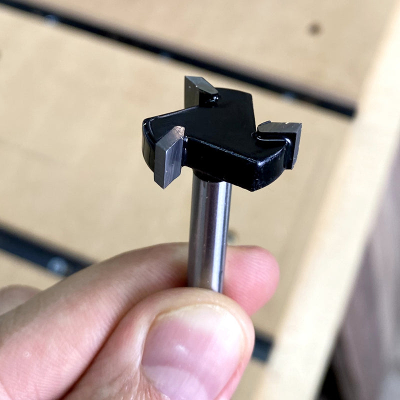 Someone holding the Flycut bit close up with a wood background 